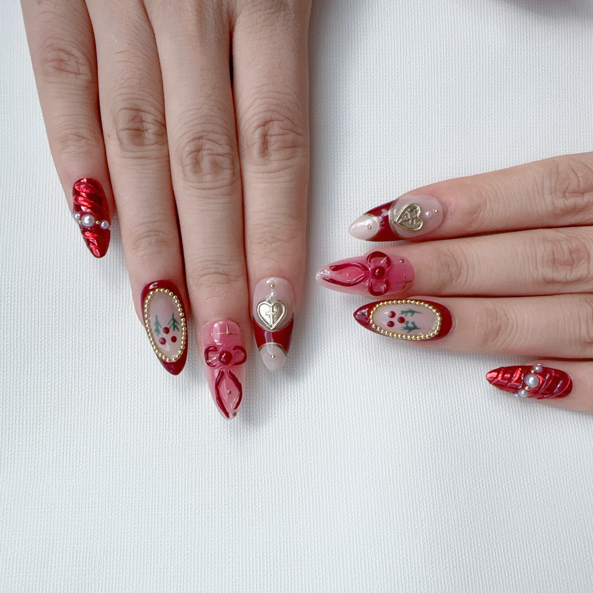 Full set wear display of Deck the Nails festive red and gold heart almond nails