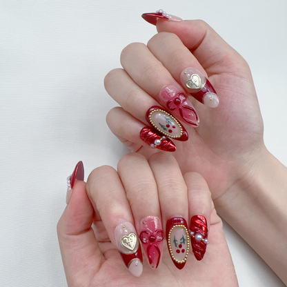 On-hand try-on of Deck the Nails showing 3D gold heart charms and red ribbon bows