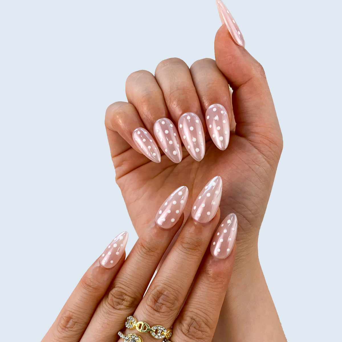 On-hand try-on of Polka Muse nails showing clean white dot lines and nude gloss