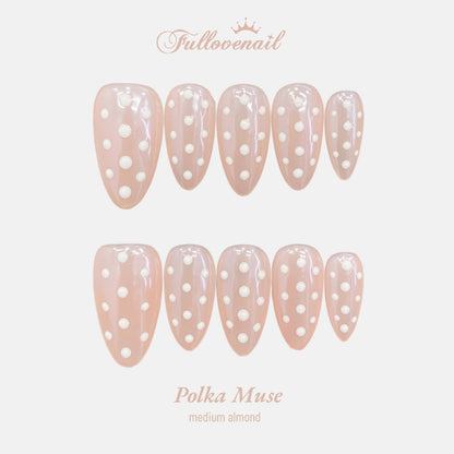 Polka Muse medium almond press-on nails with white dots over sheer nude jelly base