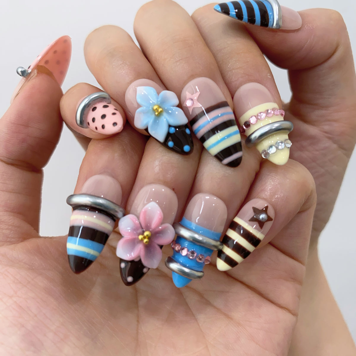 On-hand try-on of Blossom Armor Ring nails showing 3D silver bangles and stripes