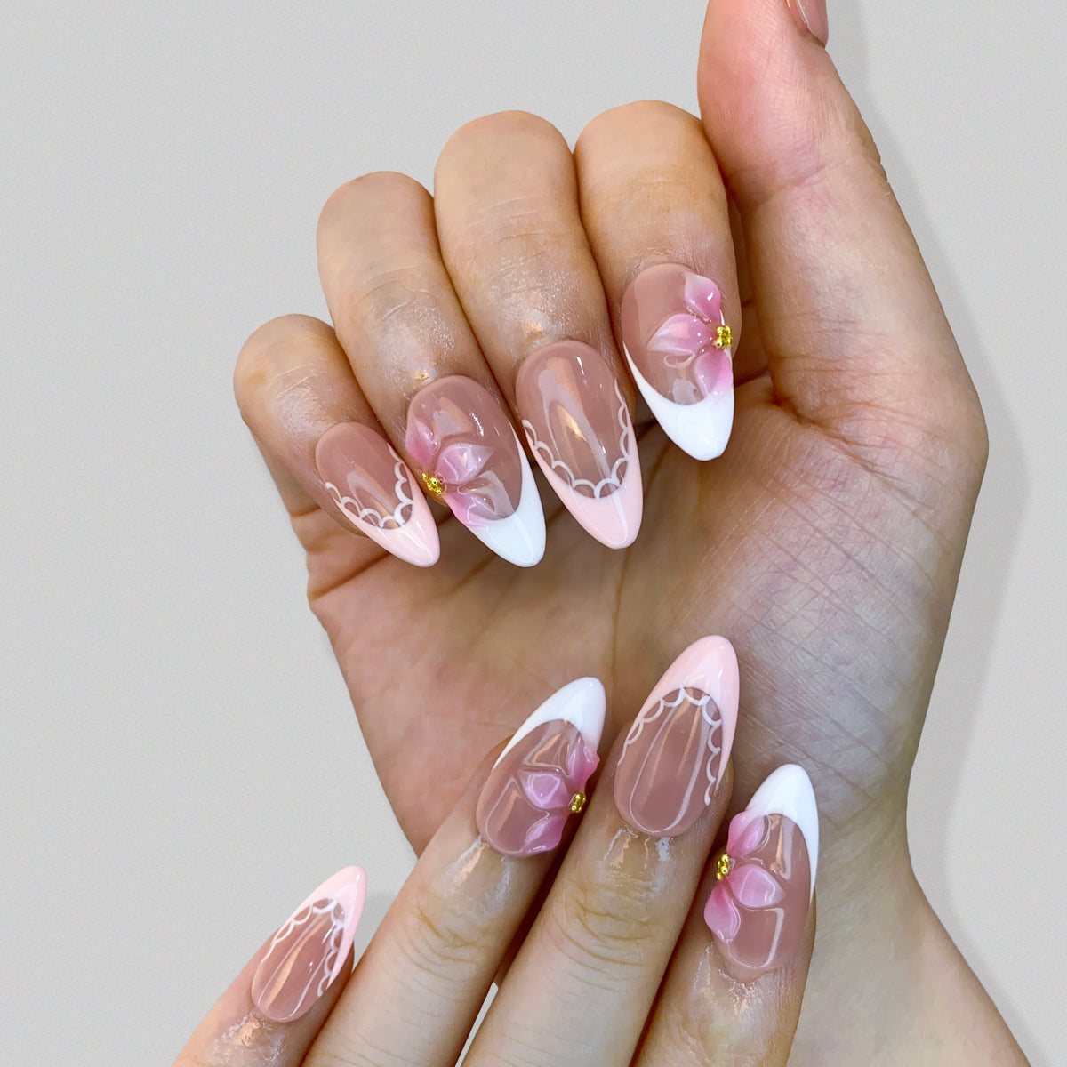 Single hand wearing Ballet Bloom French press-on nails in natural light