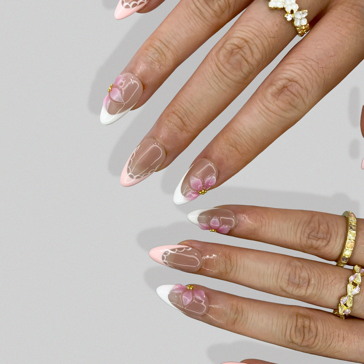 Ballet Bloom floral French press-on nails styled with gold rings on hand