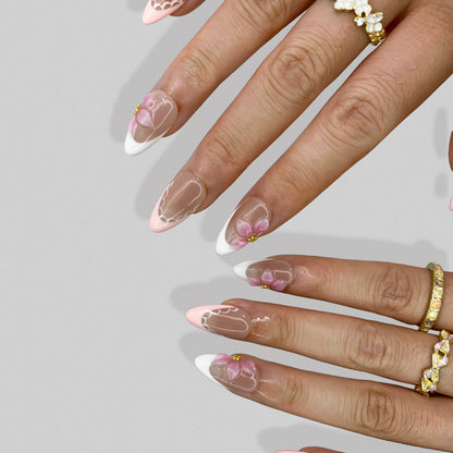 Ballet Bloom floral French press-on nails styled with gold rings on hand