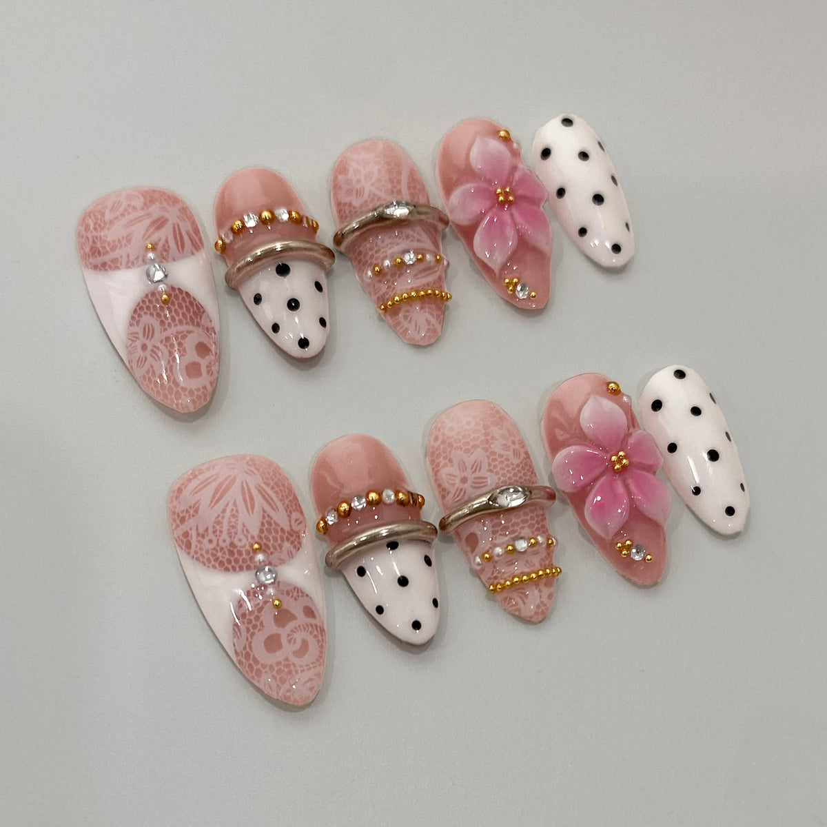 Angled view of Retro Coquette nails showing 3D pink blossom and gold bangle rings