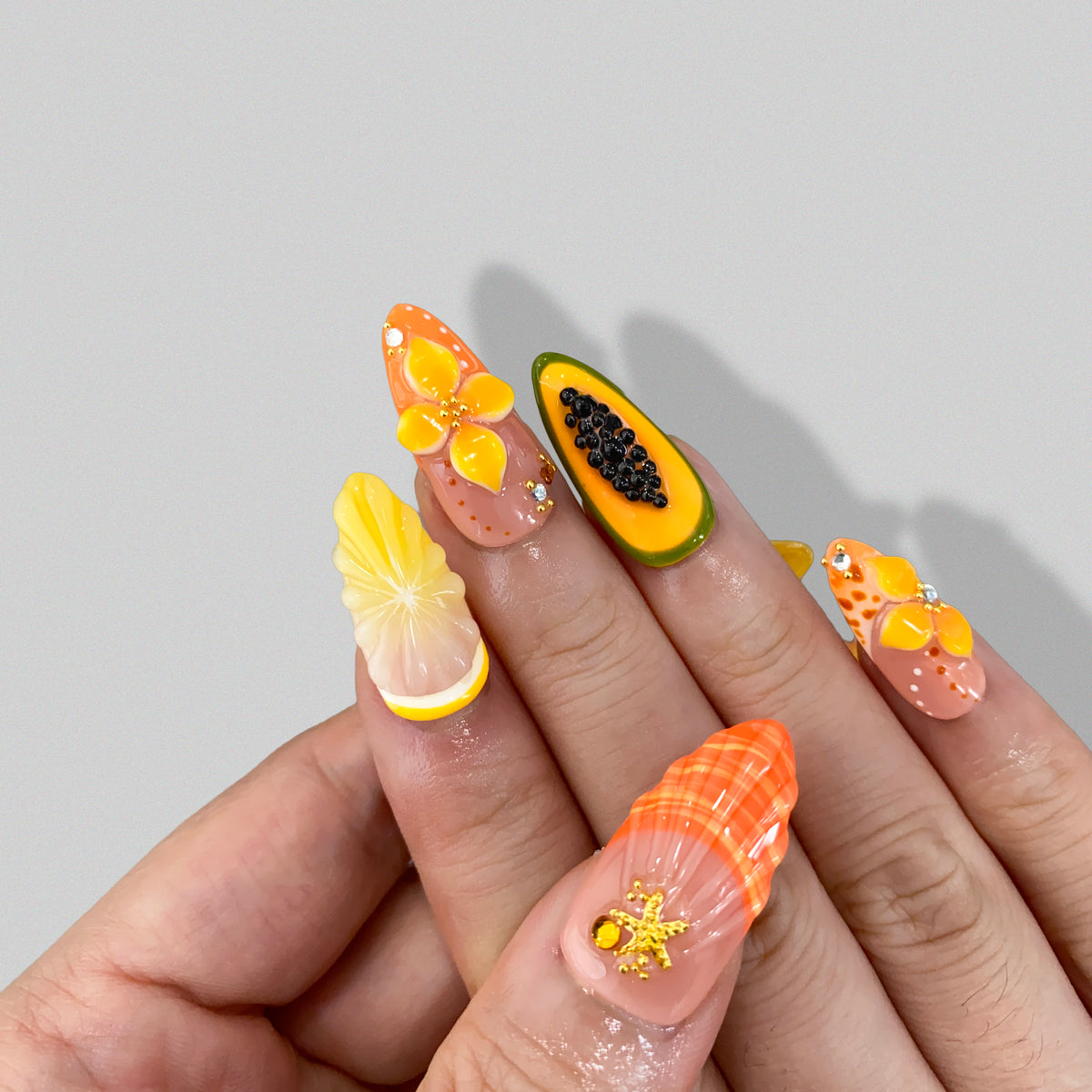 Angled view of Papaya Splash nails displaying 3D orange flower and lemon pulp art